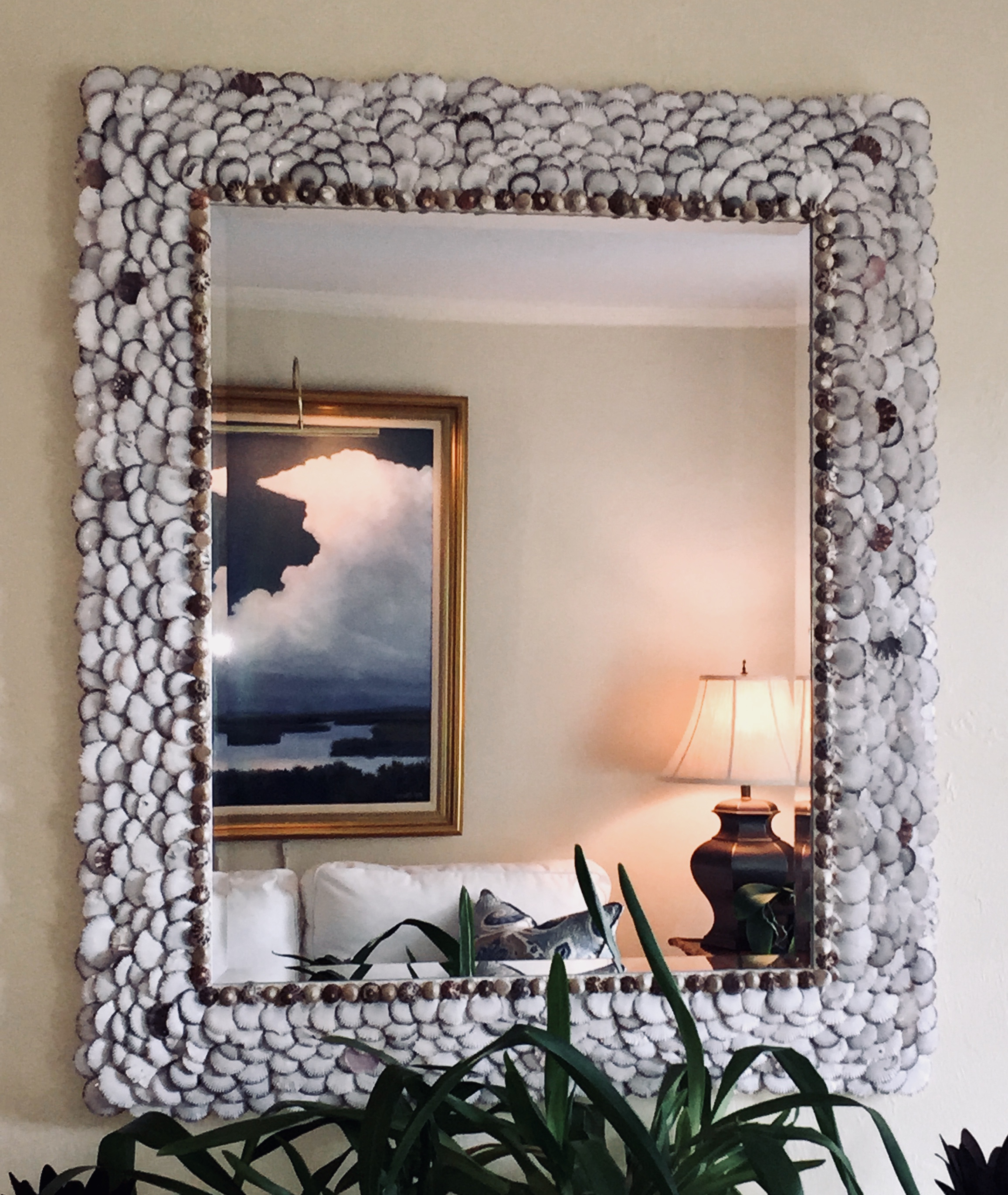 large shell mirror made with lavender scallop shells reflecting a painting with white clouds