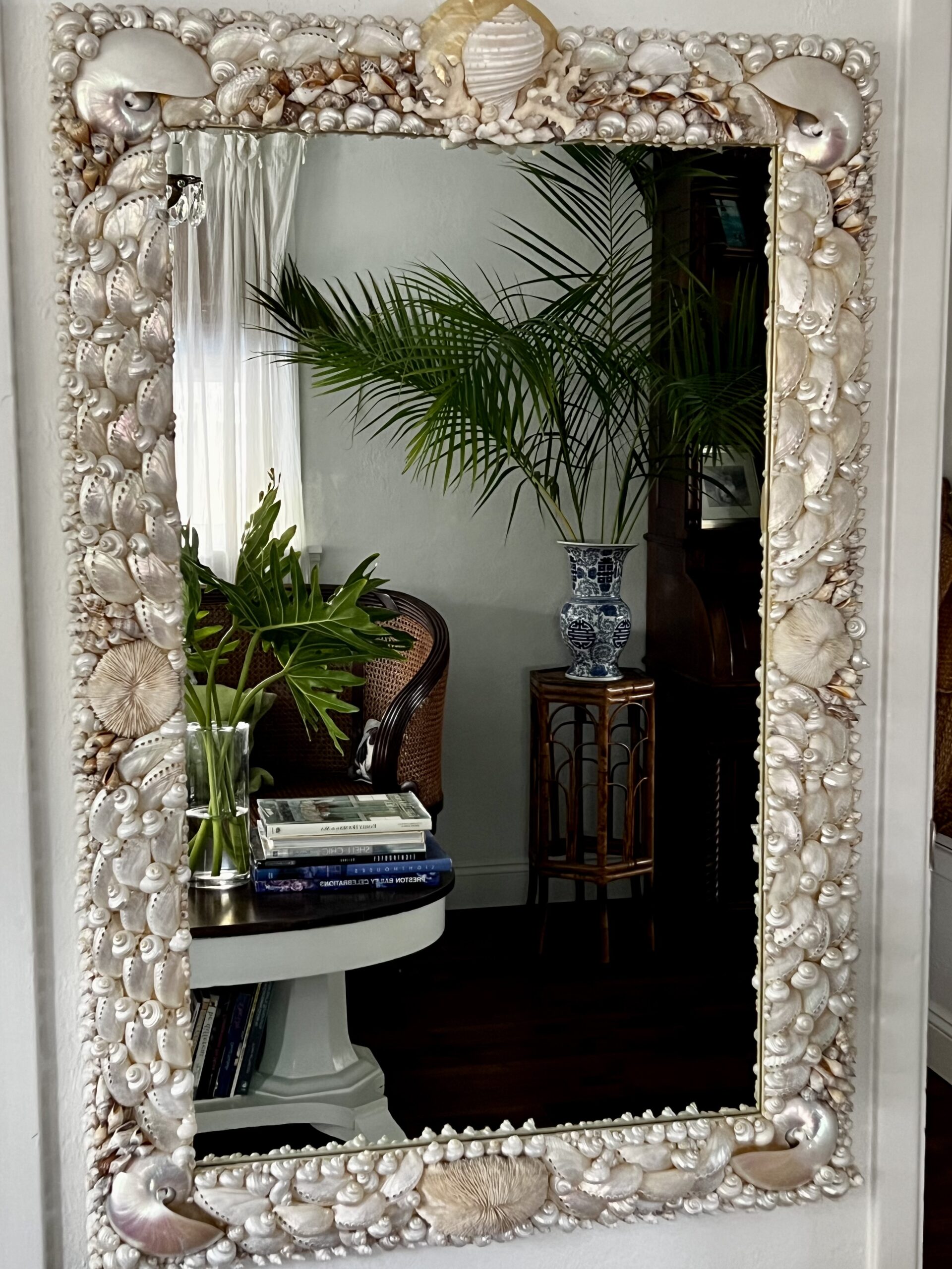 Large mirror made with white shells. Palm trees reflected.